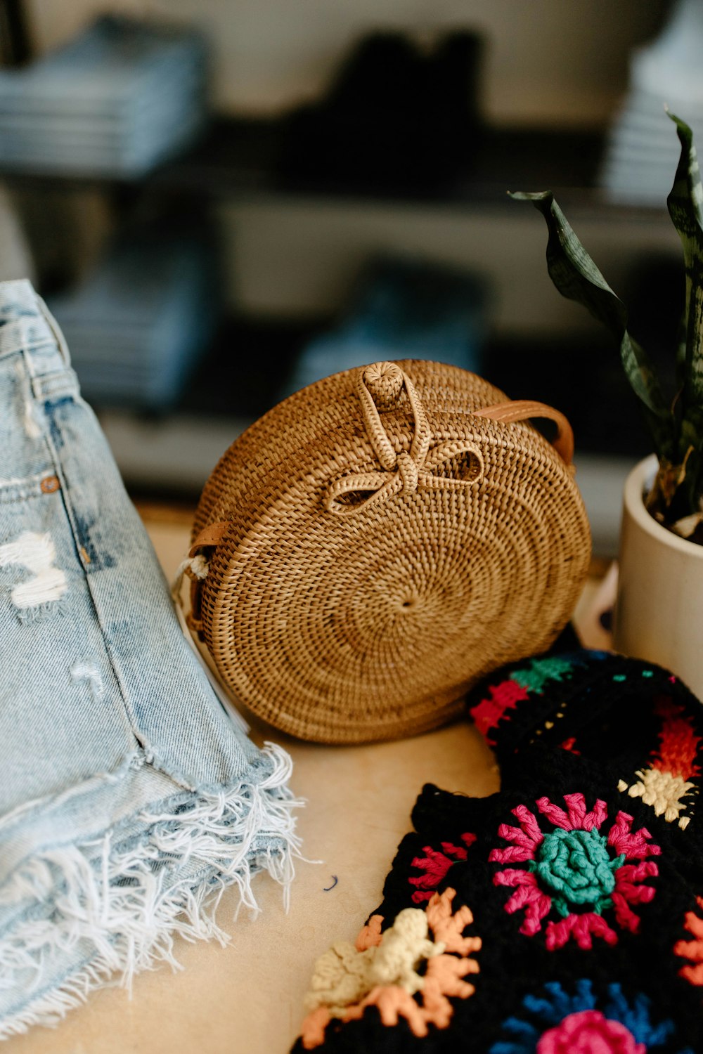 uma bolsa de crochê sentada em cima de uma mesa ao lado de um vaso