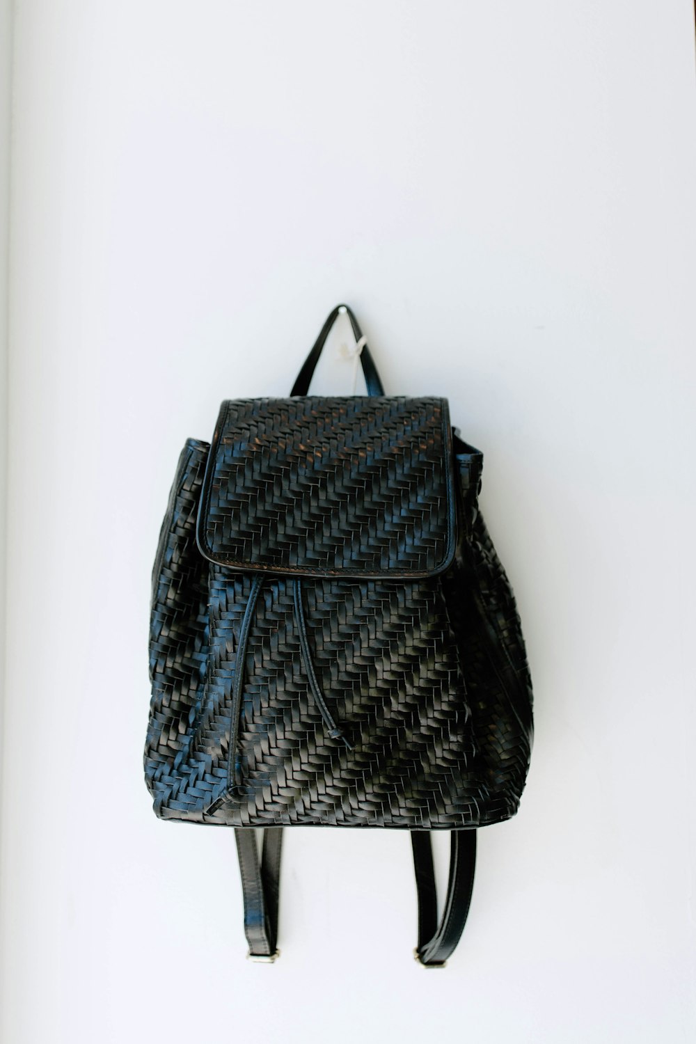 a black backpack hanging on a white wall
