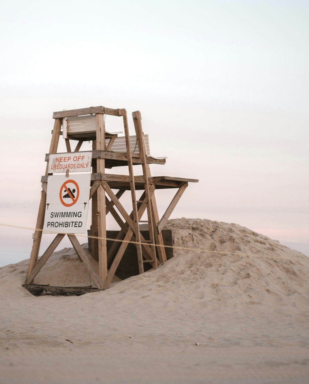 a wooden lifeguard tower sitting on top of a sandy beach