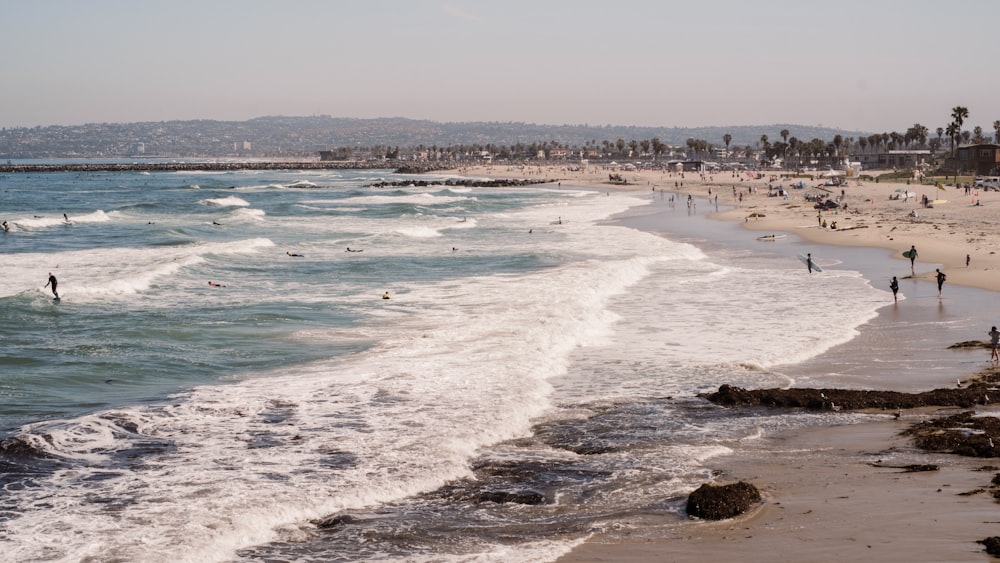 a crowded beach with people swimming in the ocean