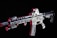 A modern rifle with a sleek design is set against a dark background. The gun features various attachments, including an optical sight on top and a flashlight mounted on the side. Metallic surfaces are highlighted with shades of red, adding contrast and depth to the appearance.