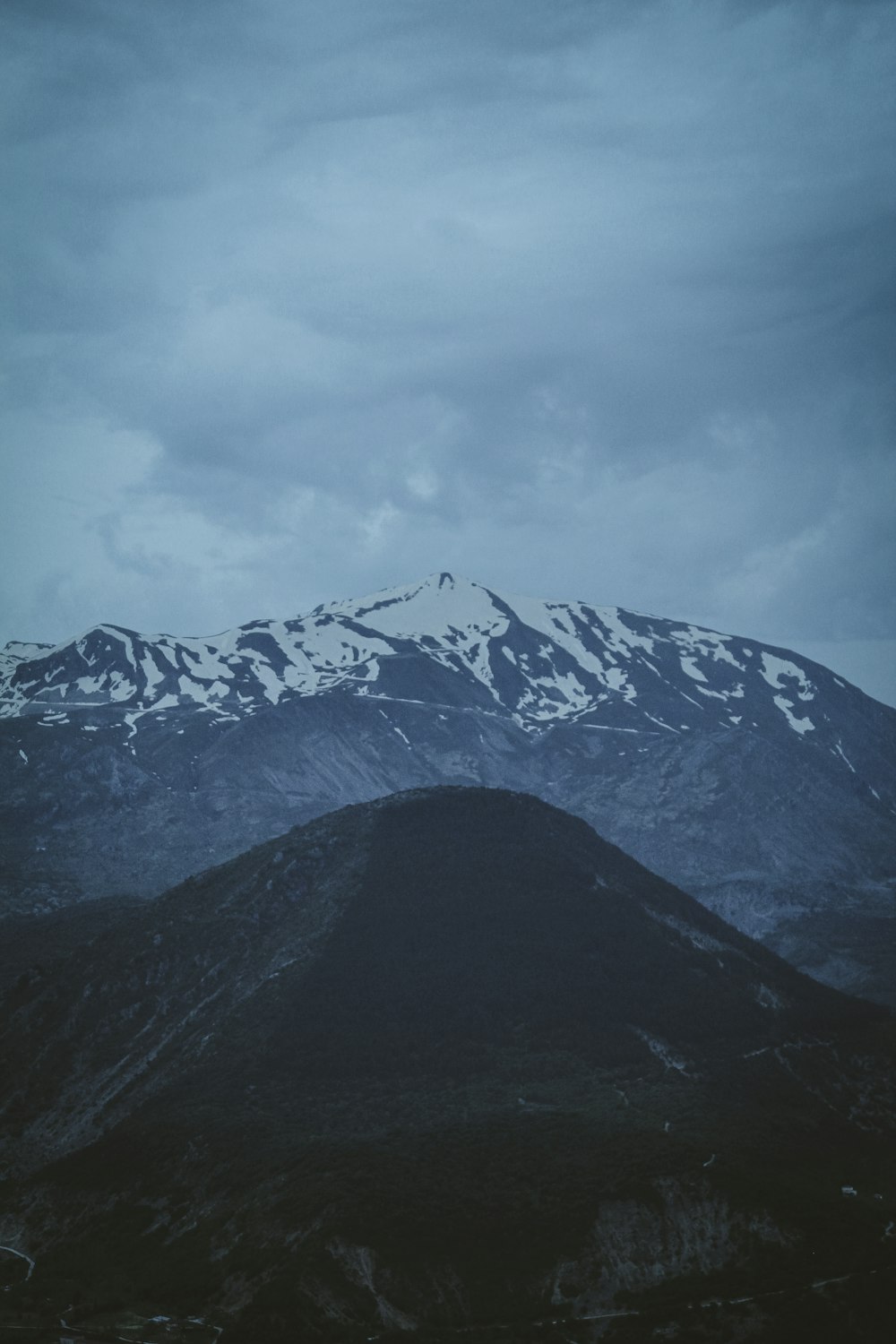 a snow covered mountain range under a cloudy sky