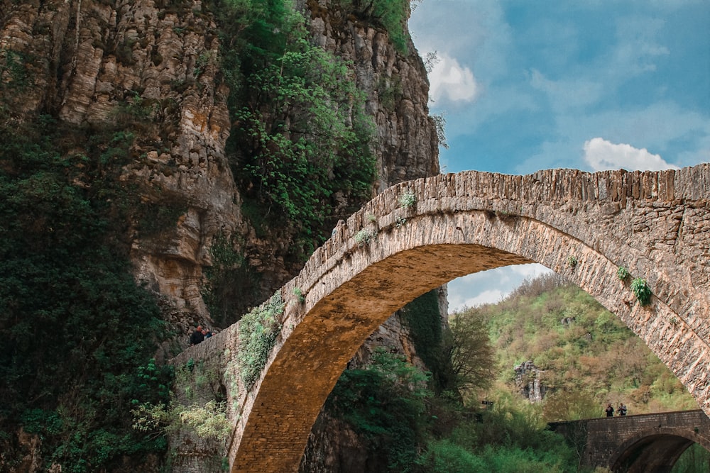 a stone bridge over a river with a cliff in the background