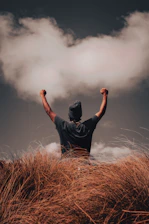 a man standing on top of a grass covered hill