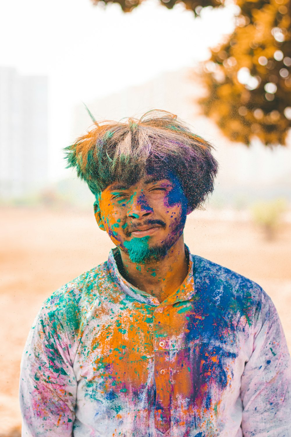 a man covered in colorful paint standing in the dirt