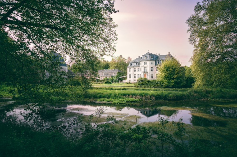 a large white house sitting next to a lush green forest