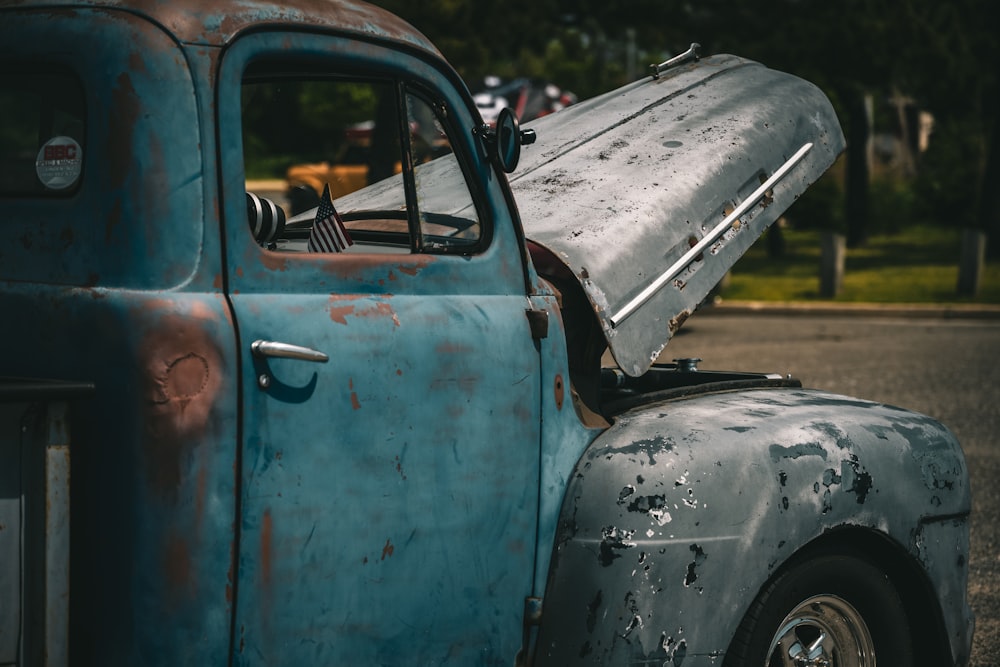 an old blue truck parked on the side of the road