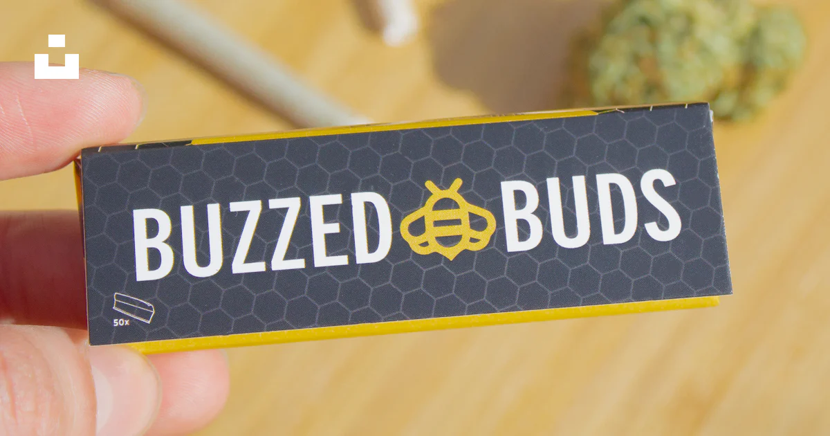 A person holding up a business card with the word buzzed buds on it ...