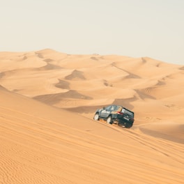 a car driving through the sand dunes in the desert