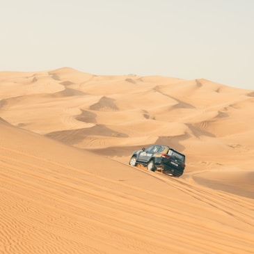 a car driving through the sand dunes in the desert