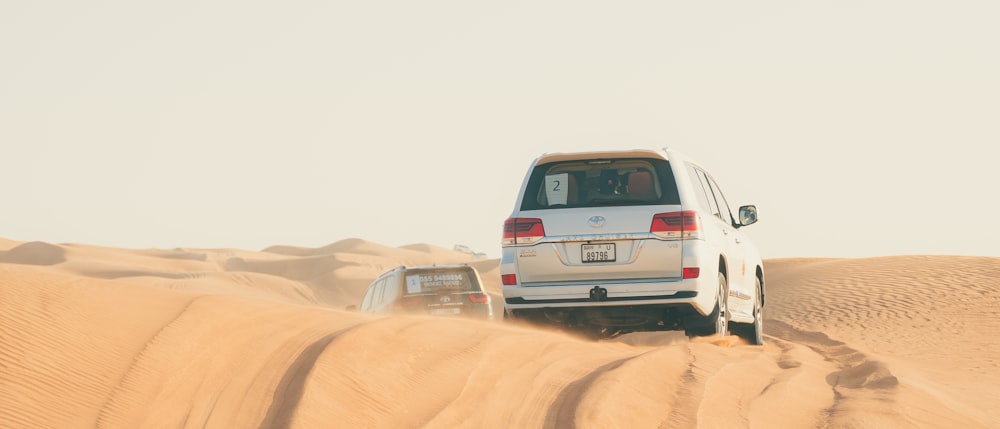 a white car driving in the sand dunes