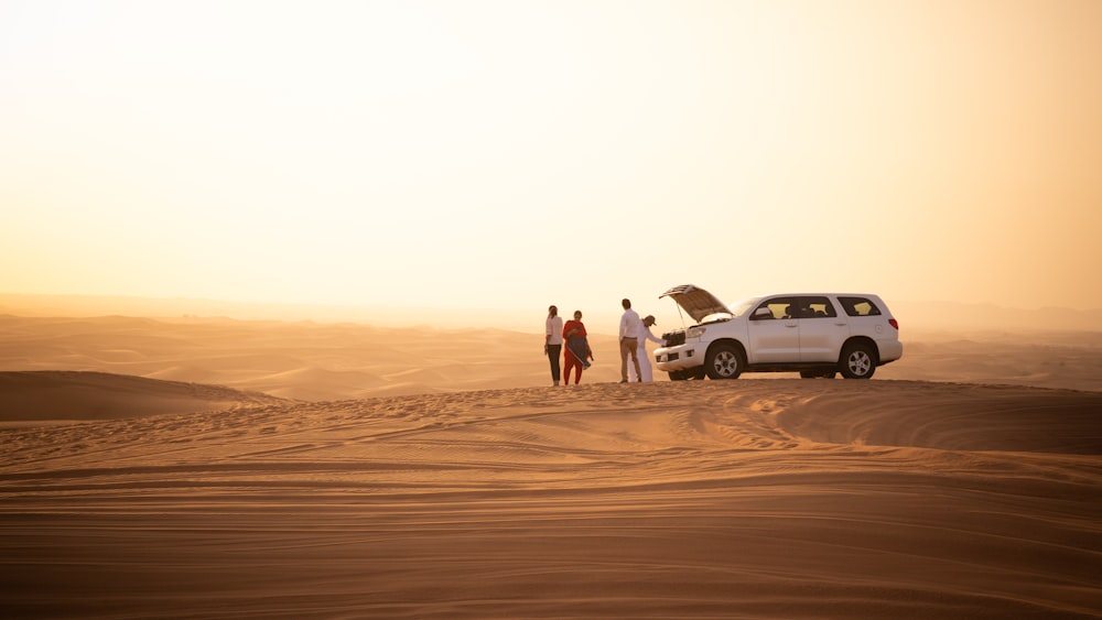 a group of people standing next to a car in the desert