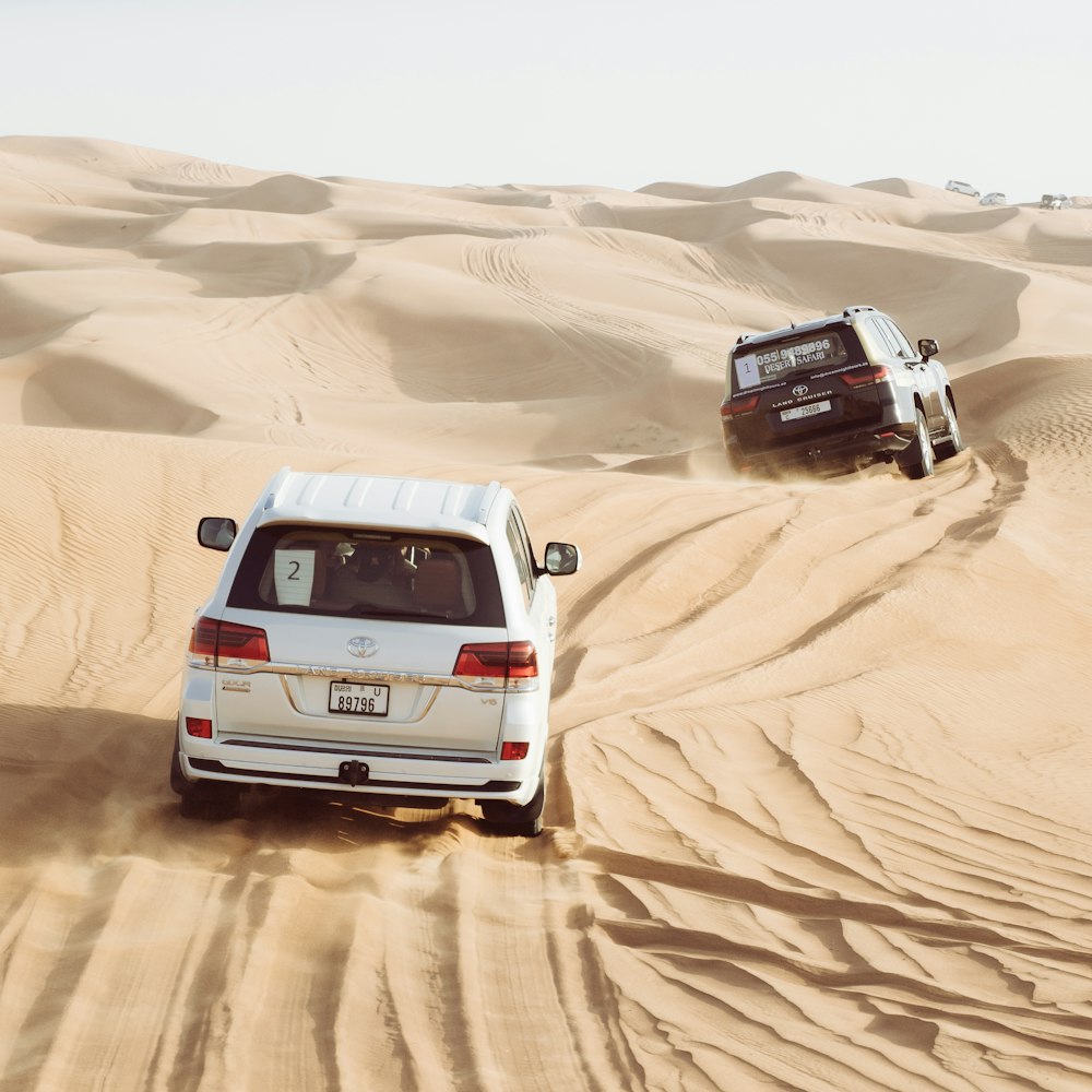 two cars driving in the sand in the desert