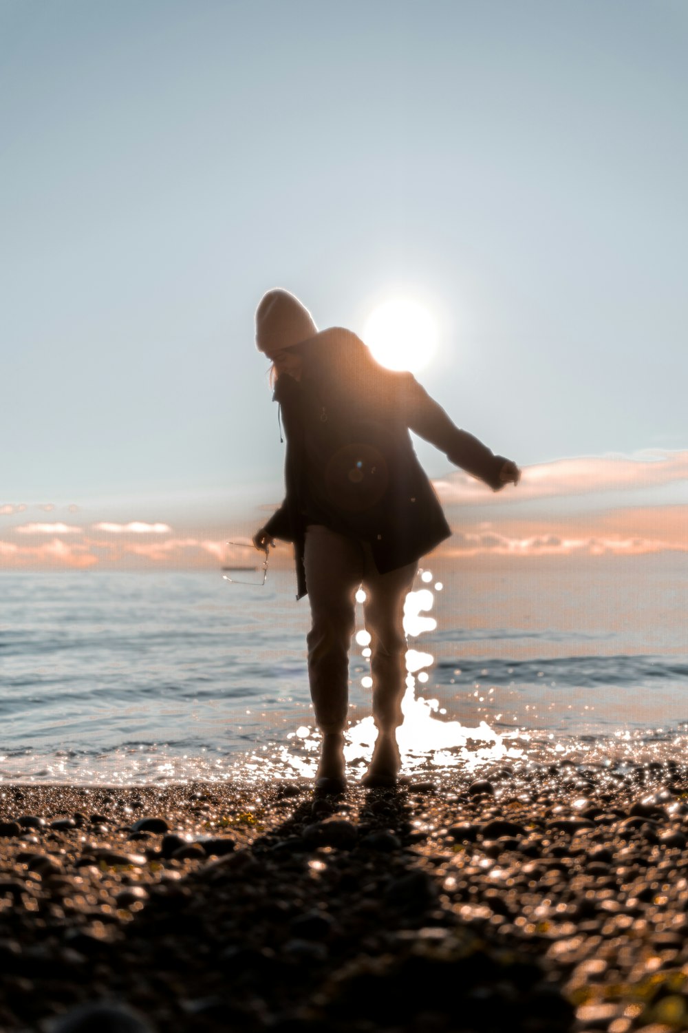 a woman standing on top of a beach next to the ocean