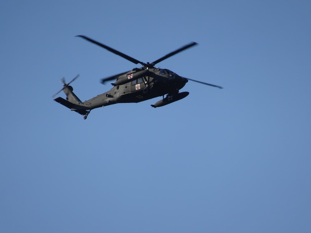 a helicopter flying through a blue sky on a clear day