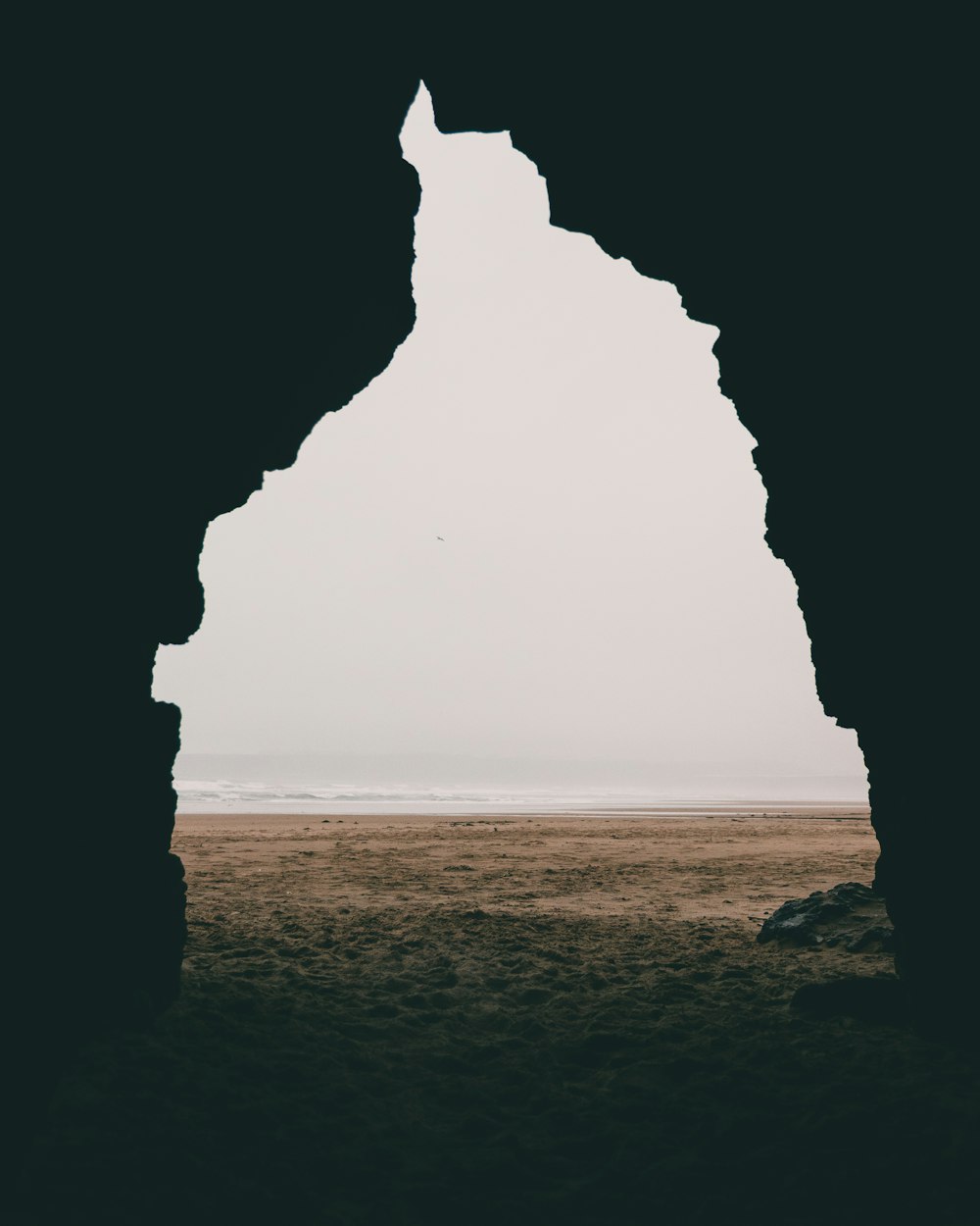 a view of a beach through an arch in the sand