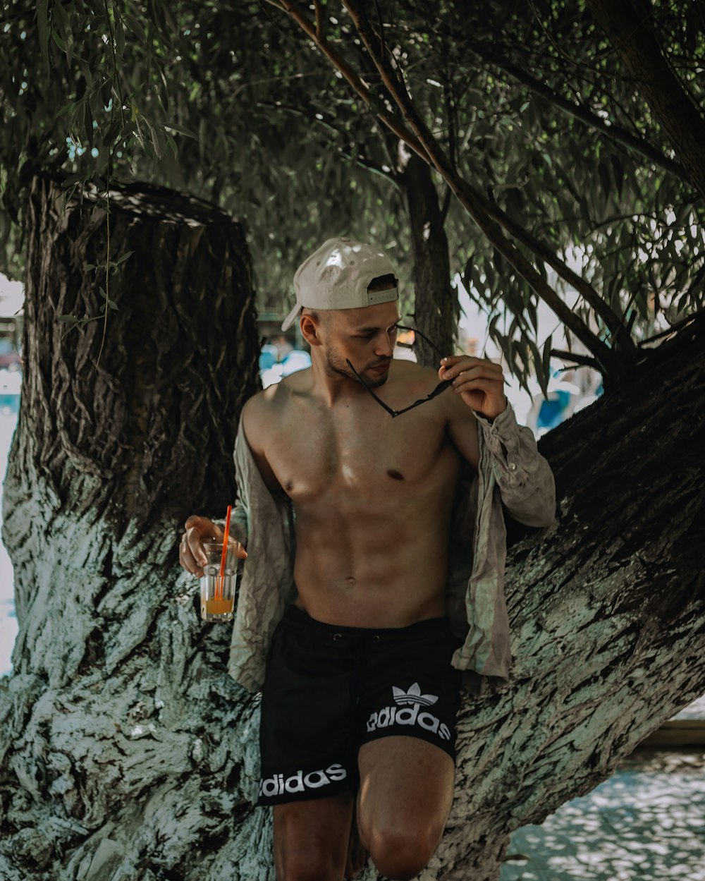a shirtless man sitting on a tree branch