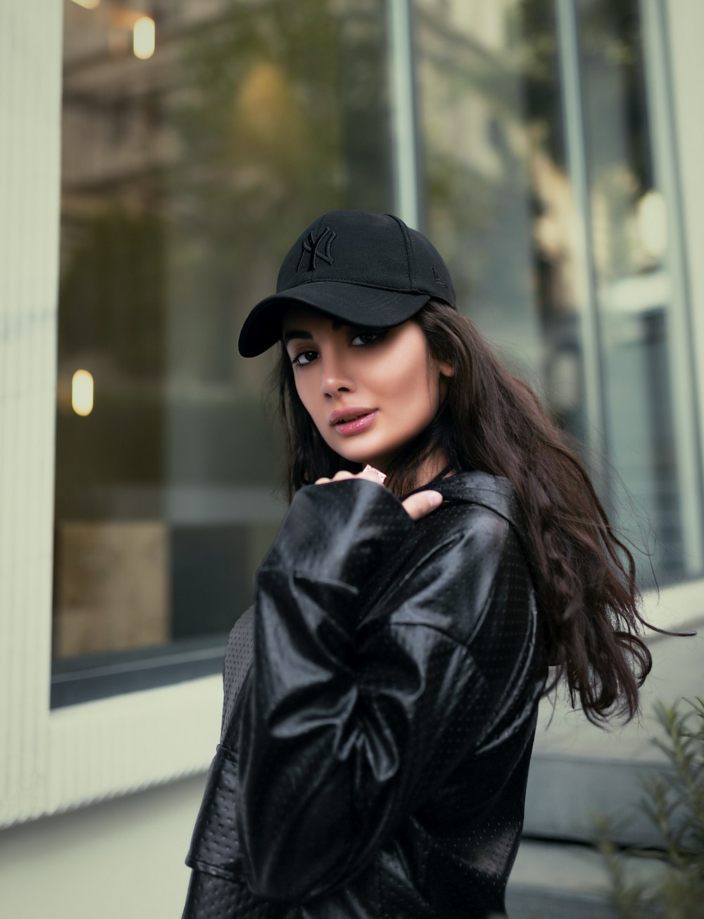 a woman in a black leather jacket and hat