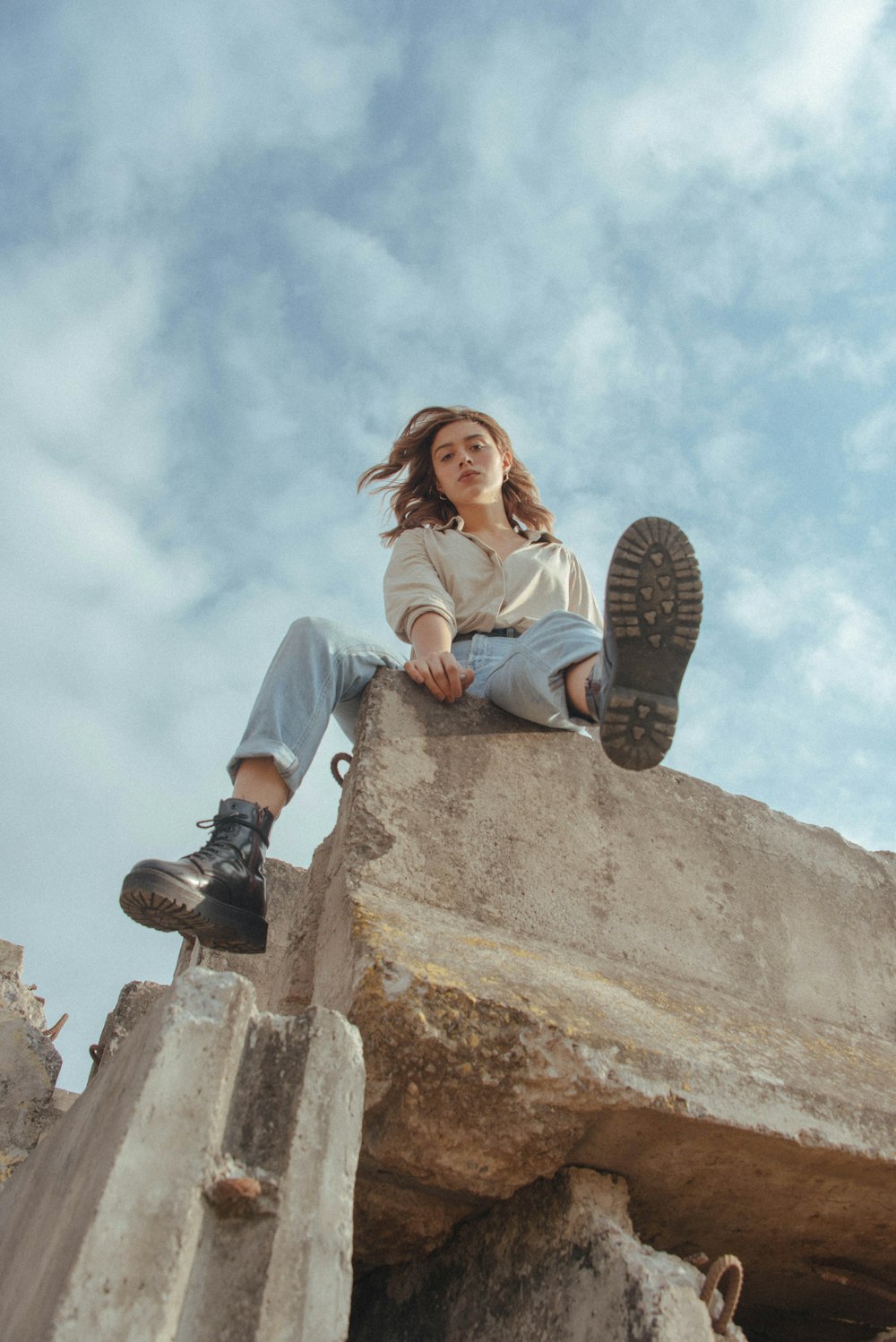 a woman sitting on top of a stone wall