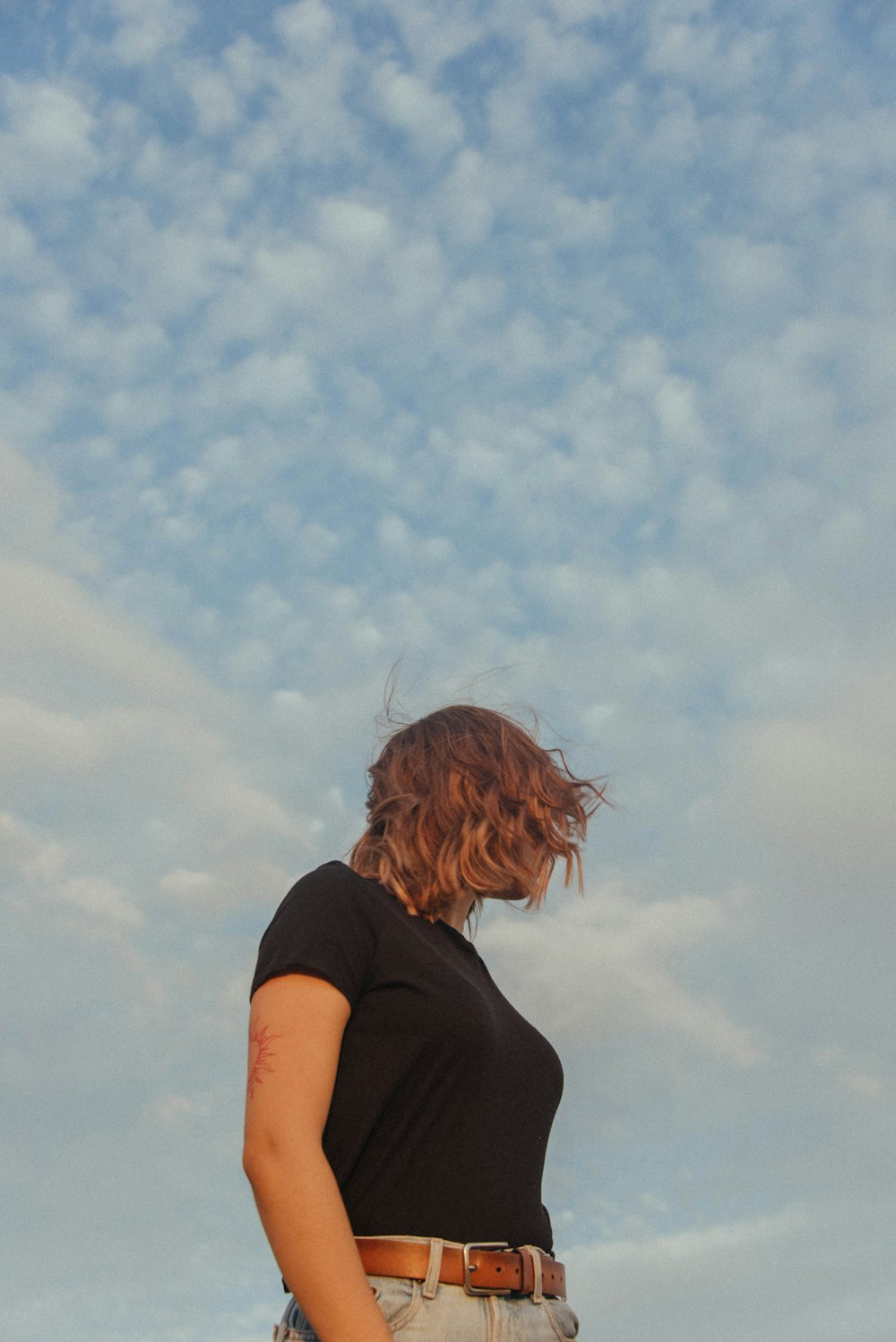 a woman in a black shirt is flying a kite