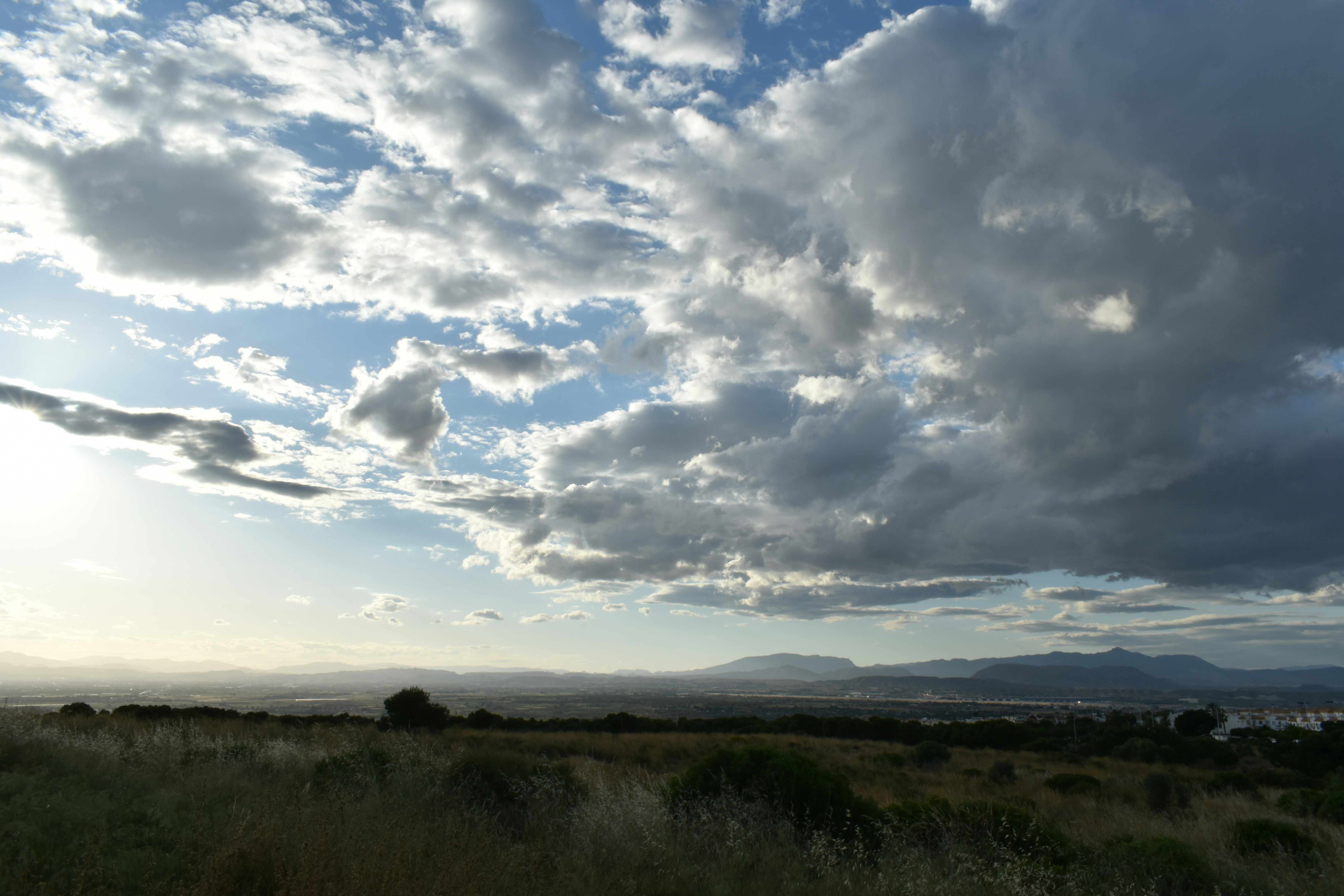 the sun is shining through the clouds over a field