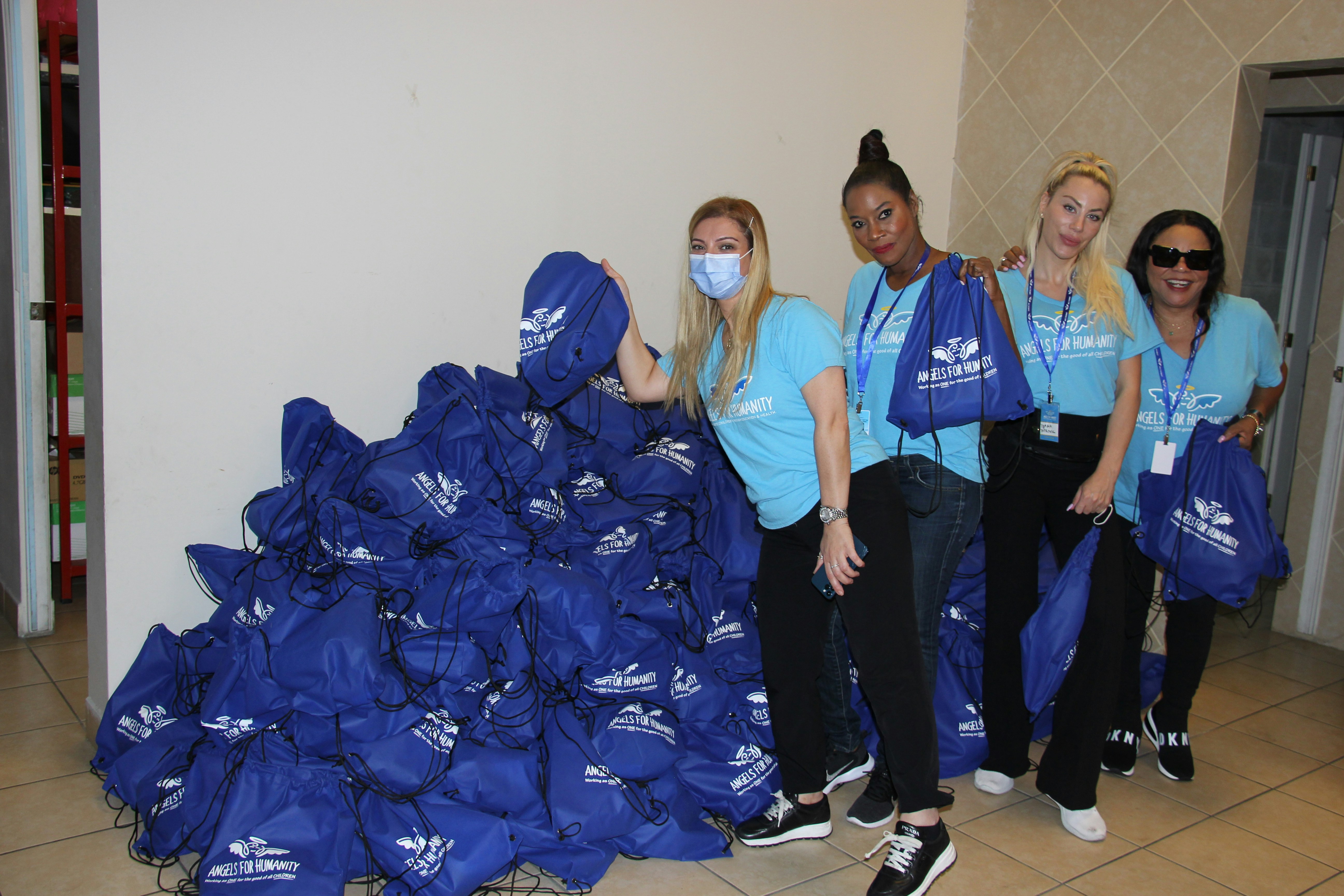 group of women standing by a pile of blue bags