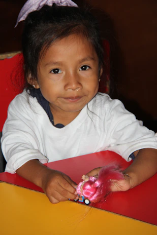 A joyful child playing with a 3D printed animal figurine at home.