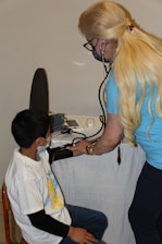 a woman is listening to a boy with a stethoscope