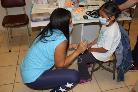 a woman in a face mask sitting next to a little girl
