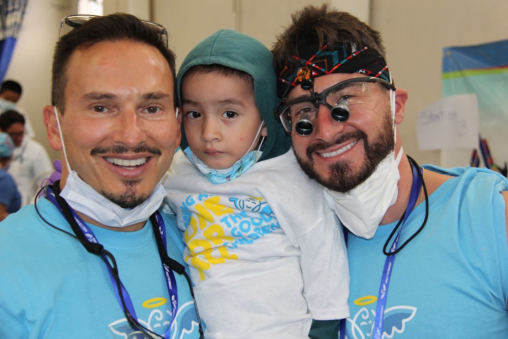 two men and a baby are posing for a picture