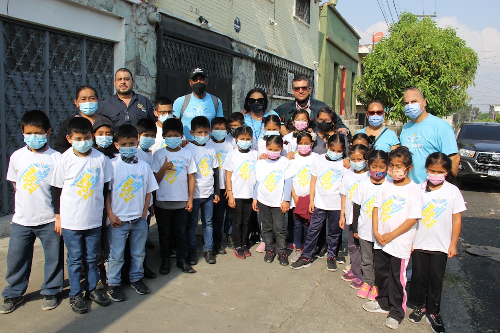 a group of children wearing face masks standing in front of a building