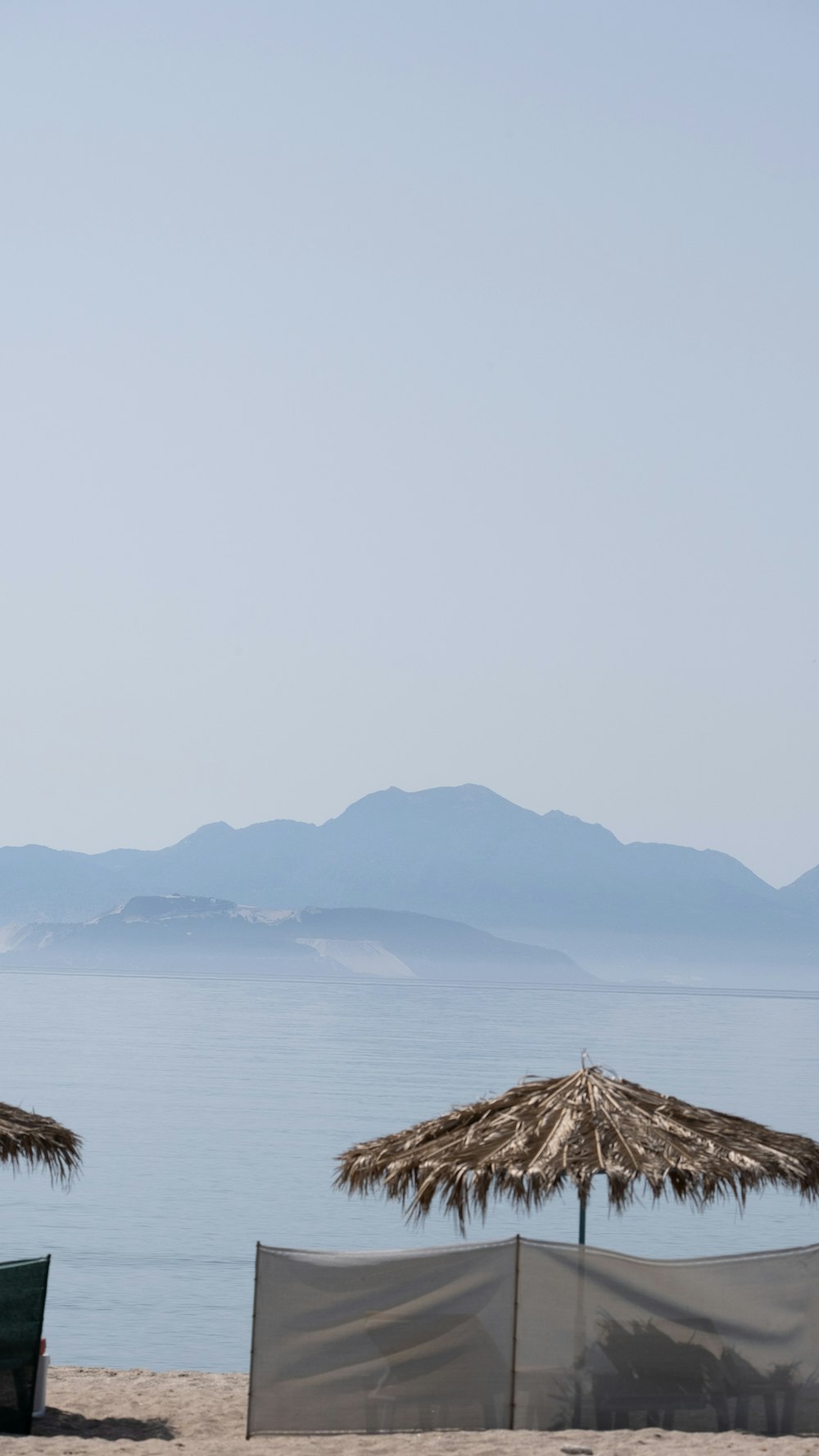 um par de guarda-sóis sentados em cima de uma praia de areia