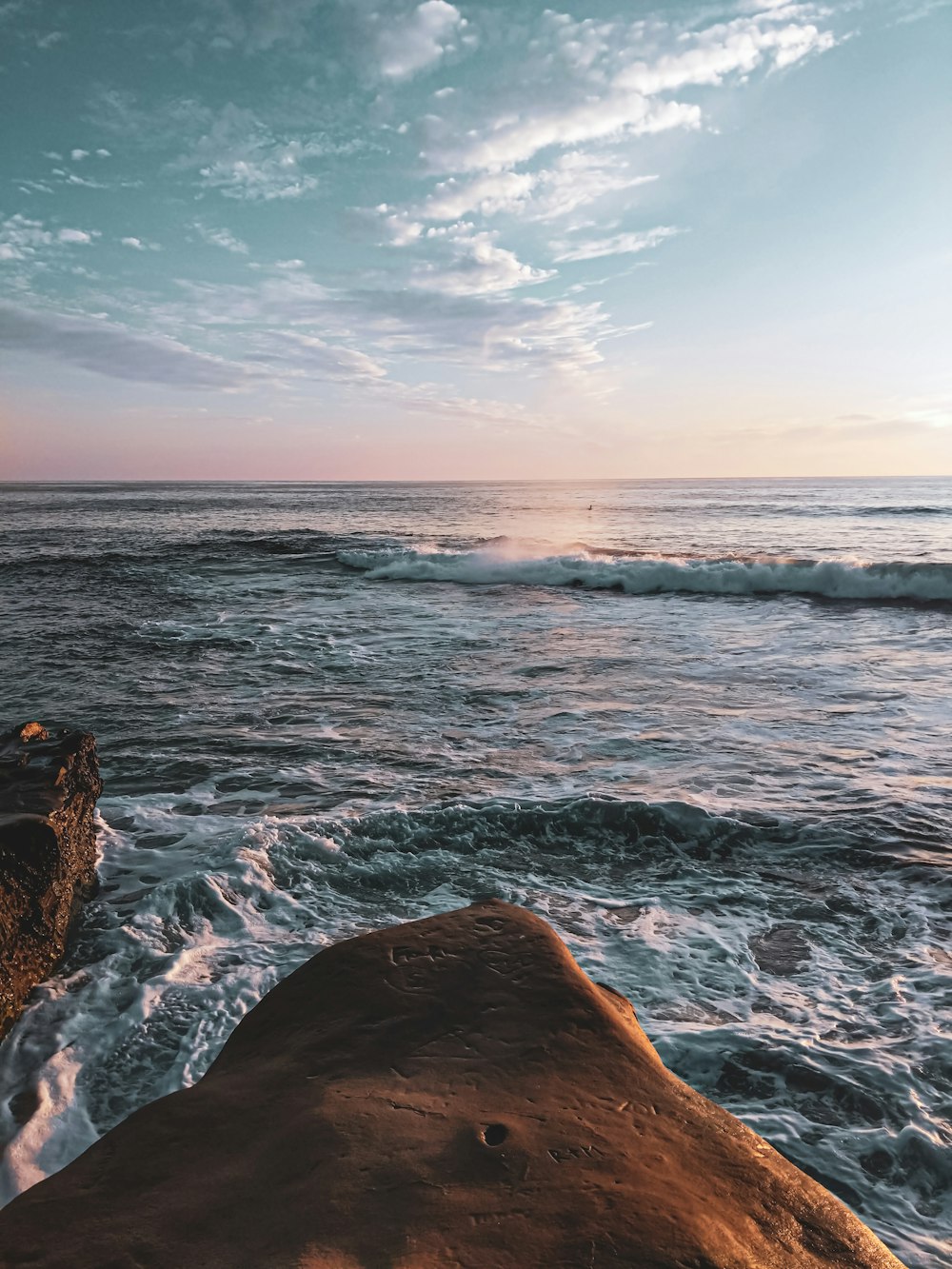 a person standing on top of a rock near the ocean