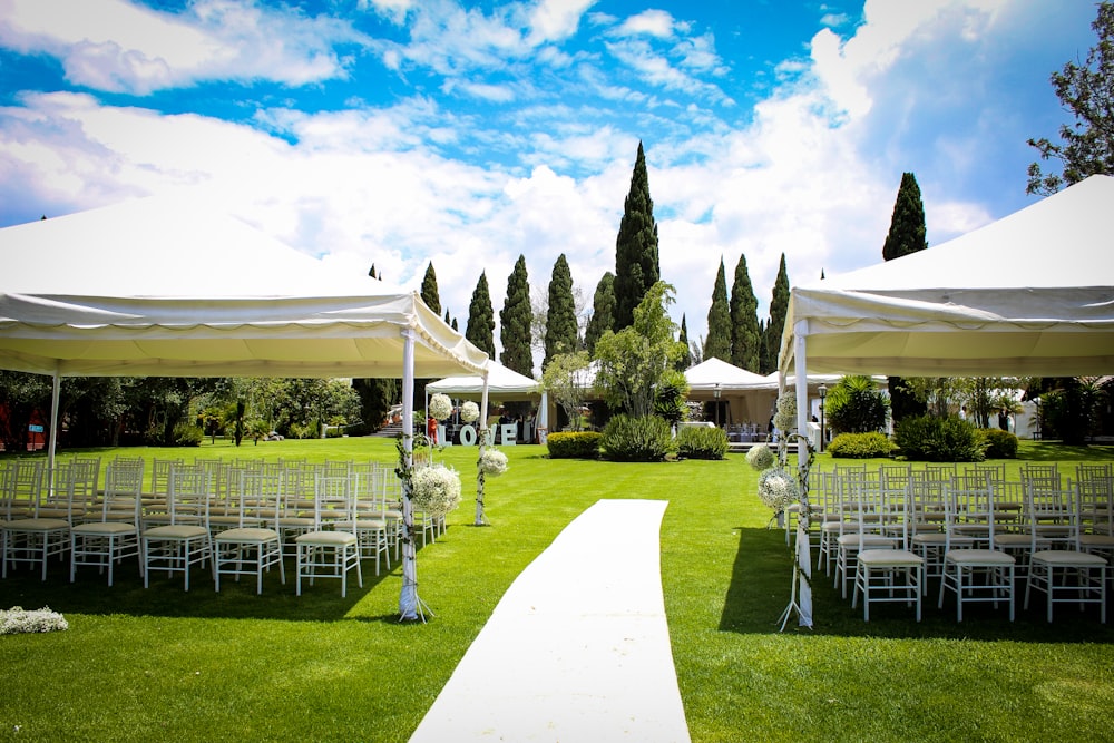 an outdoor wedding setup with white chairs and white umbrellas