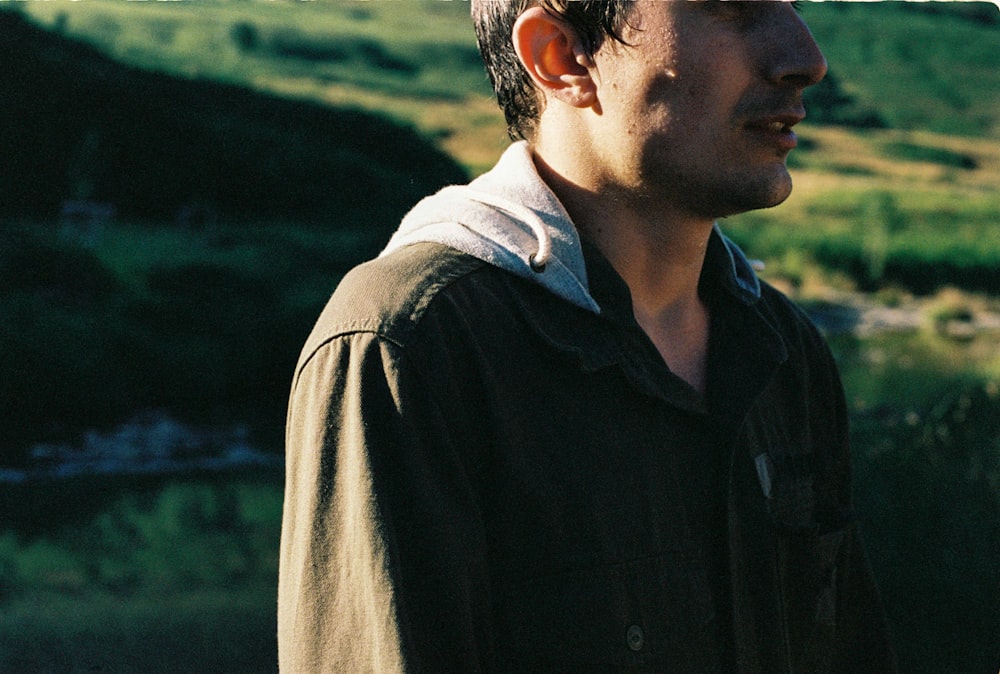 a man standing in front of a lush green hillside