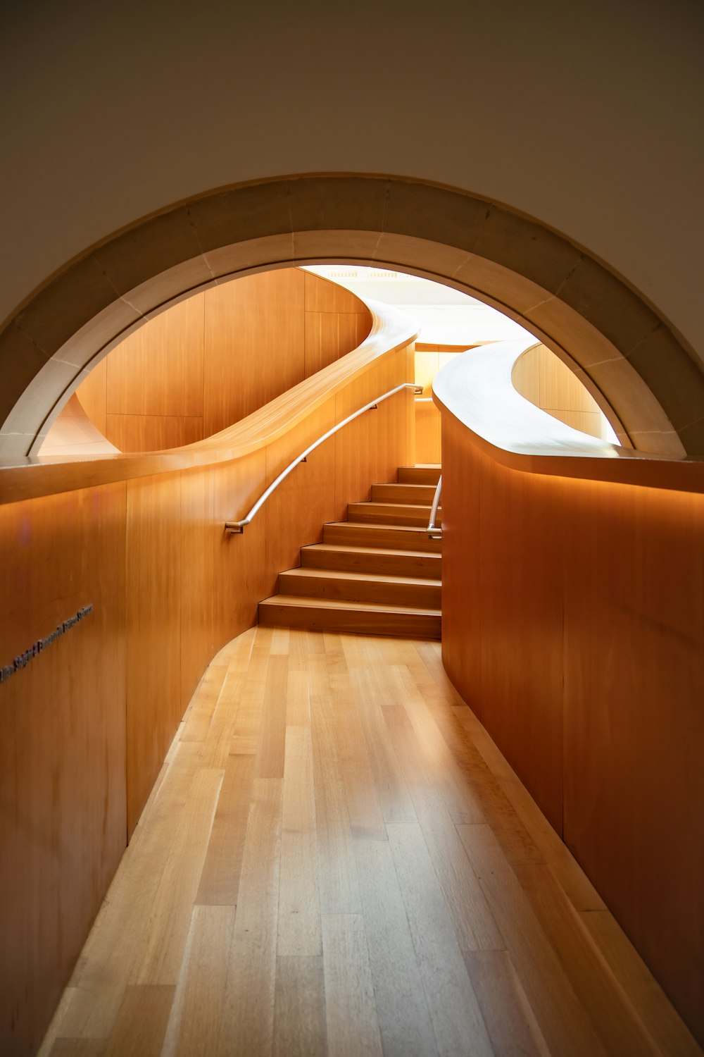 a curved wooden staircase with a light at the end