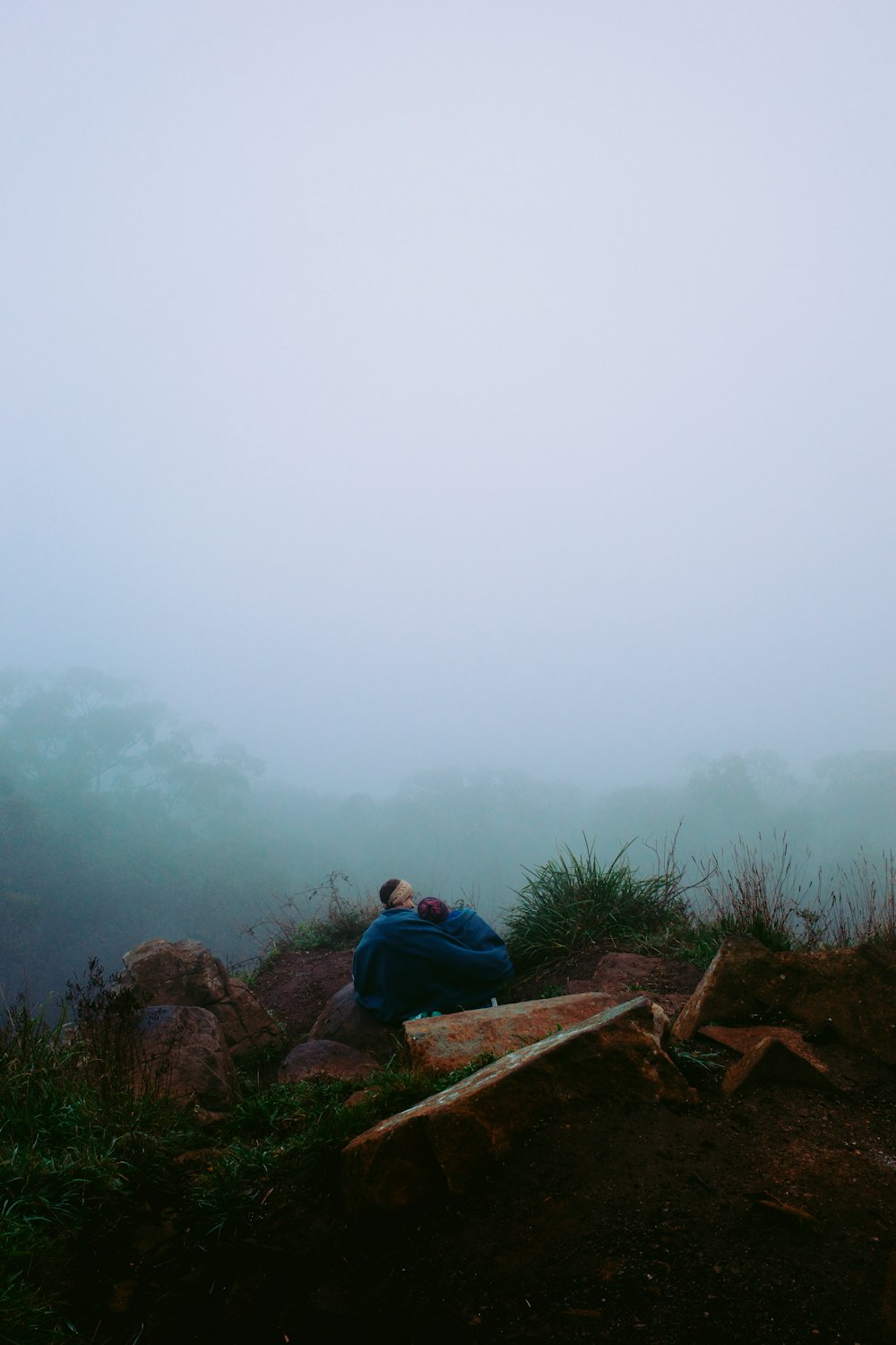 a person sitting on a rock in the fog