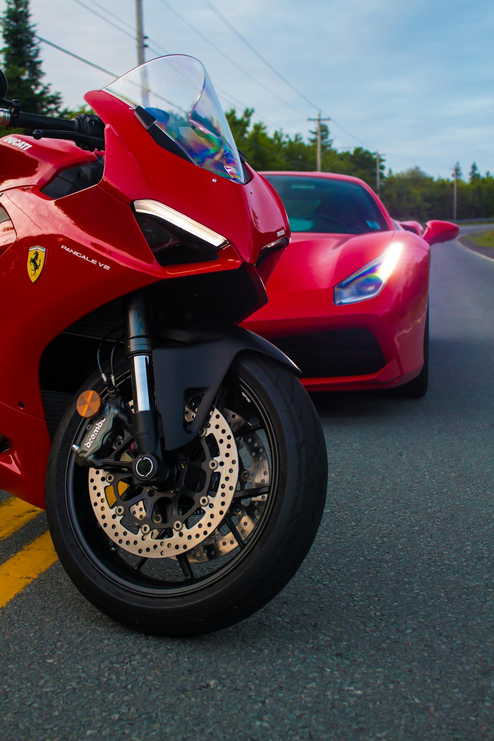 a red motorcycle parked next to a red sports car