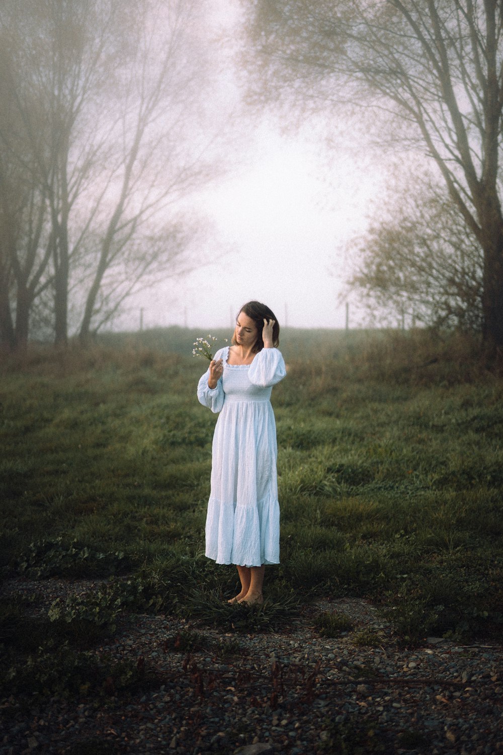 a woman in a white dress standing in a field