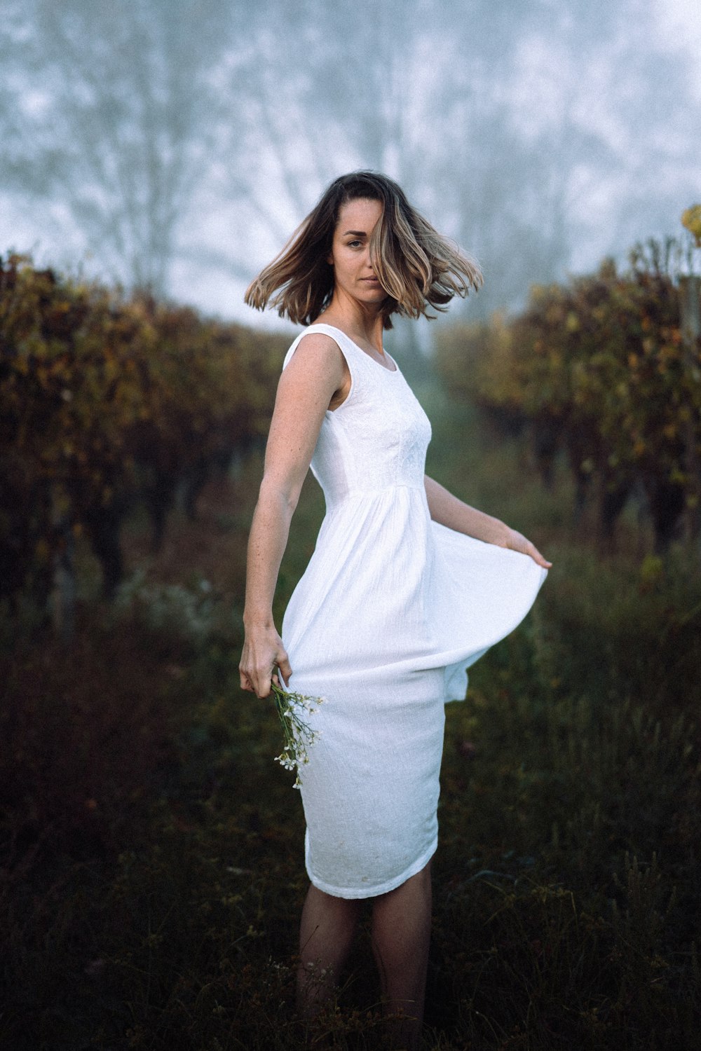 a woman in a white dress standing in a field