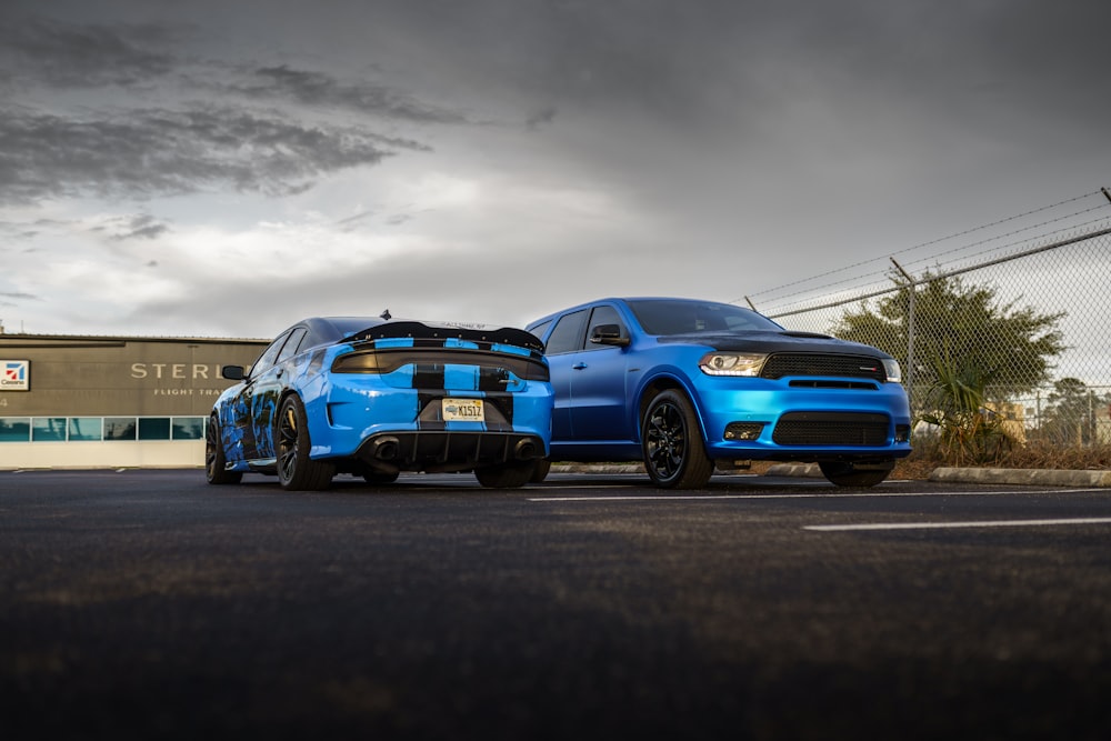 two blue cars parked next to each other on a street