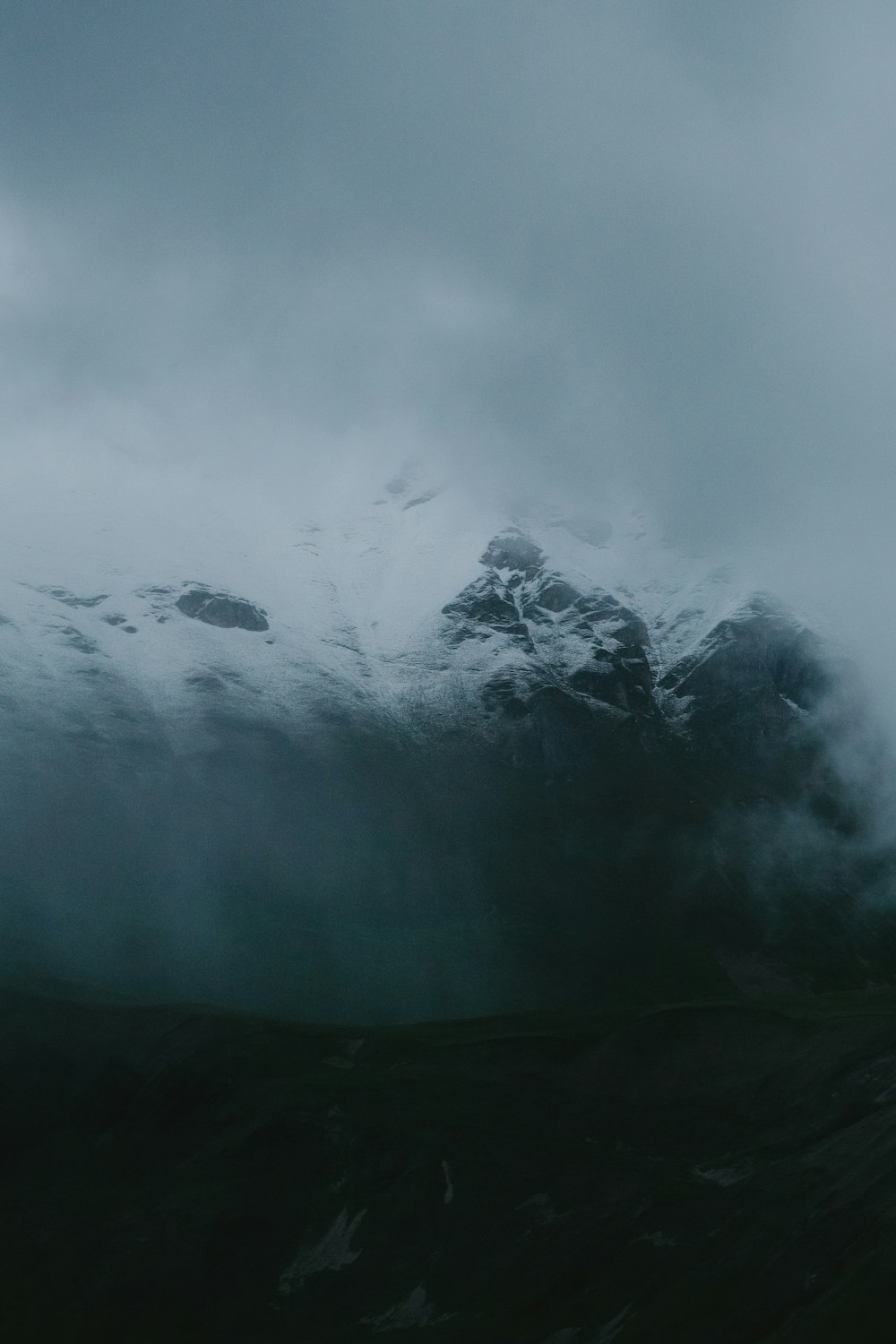 a mountain covered in snow under a cloudy sky