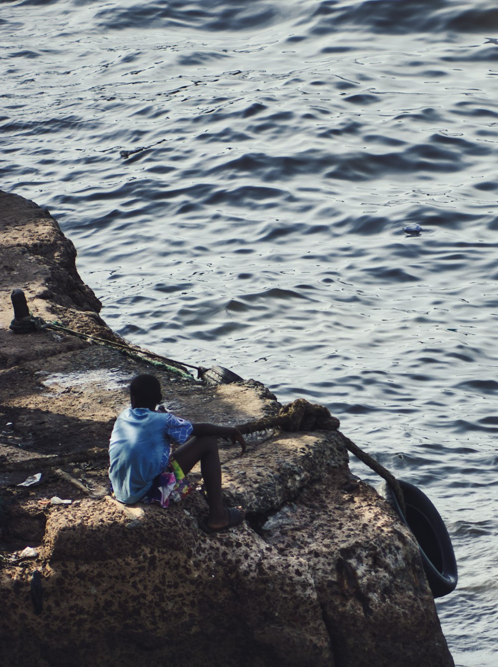 a person sitting on a rock near the water