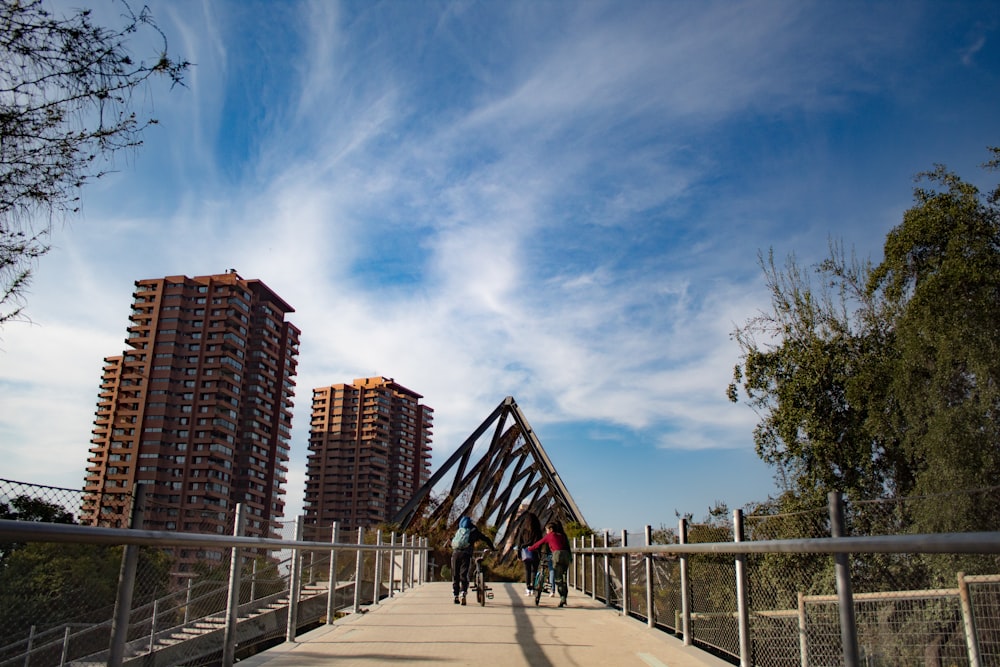 two people walking across a bridge with tall buildings in the background