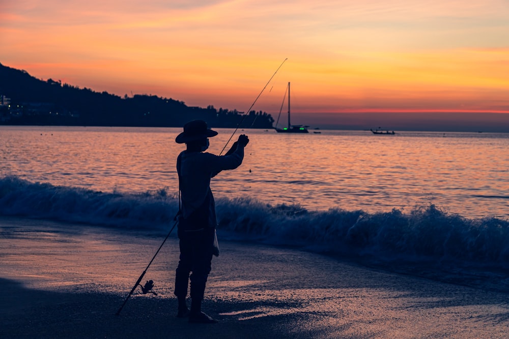 a man standing on top of a beach next to the ocean