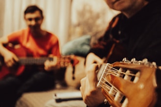 a man playing a guitar next to another man