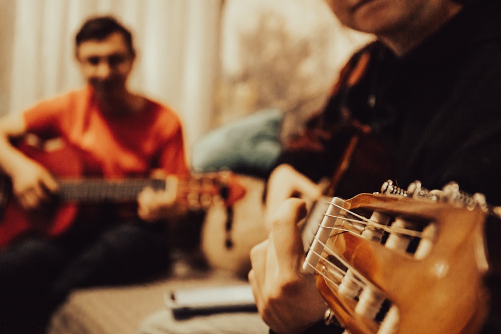 a man playing a guitar next to another man