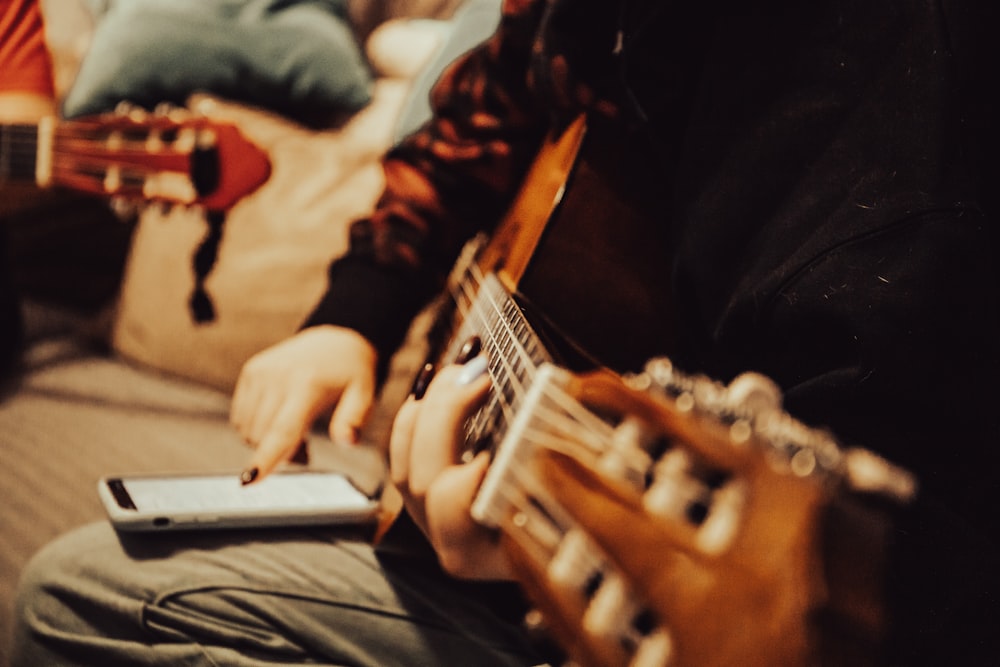 a person sitting on a couch playing a guitar