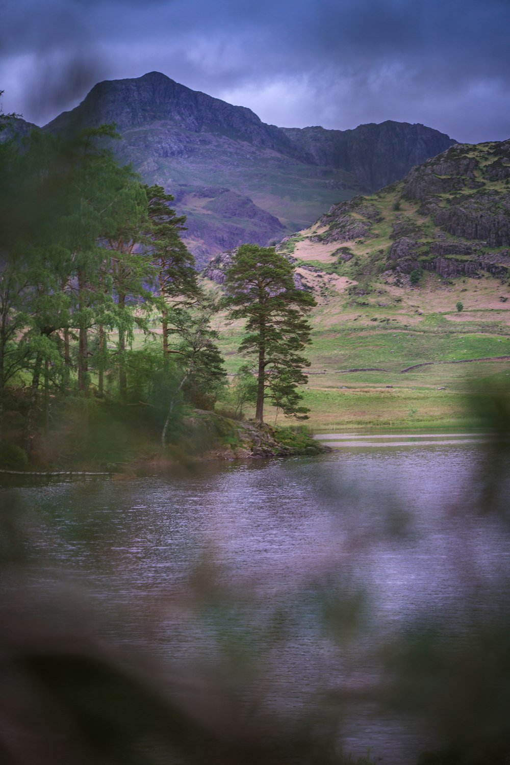 a body of water surrounded by mountains under a cloudy sky