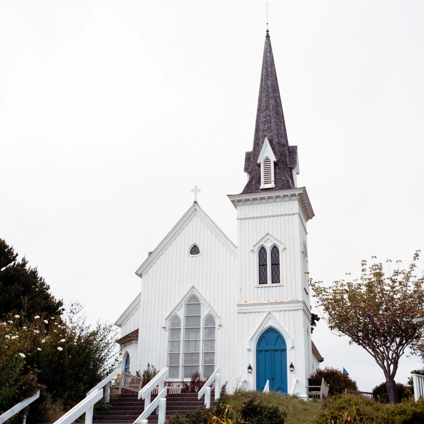 White church with a steeple and blue entrance doors, illustrating the setting for Church Security Training